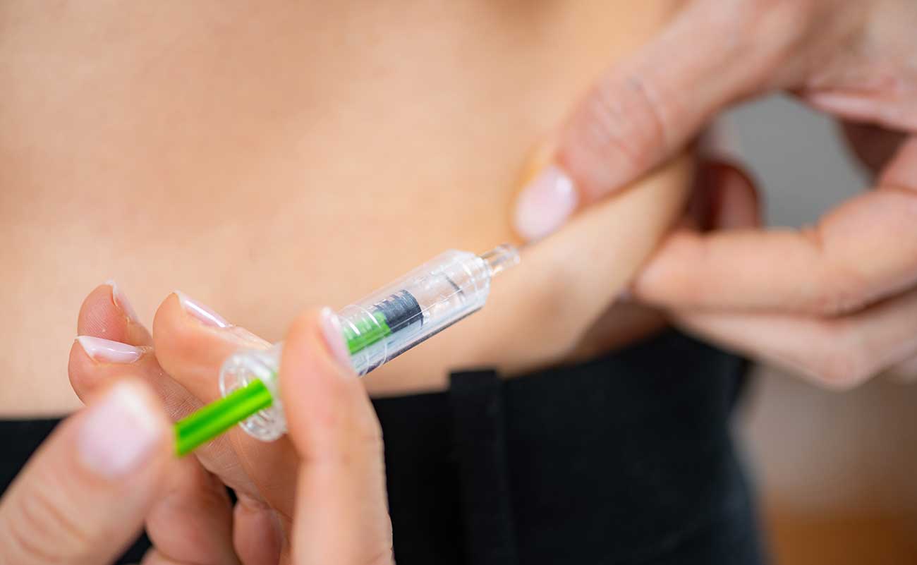 Closeup of male injecting insulin into their stomach