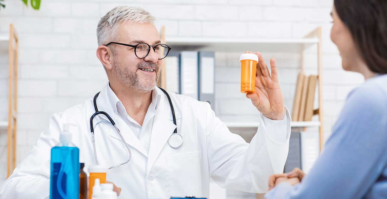 Doctor holding up pill bottle to patient