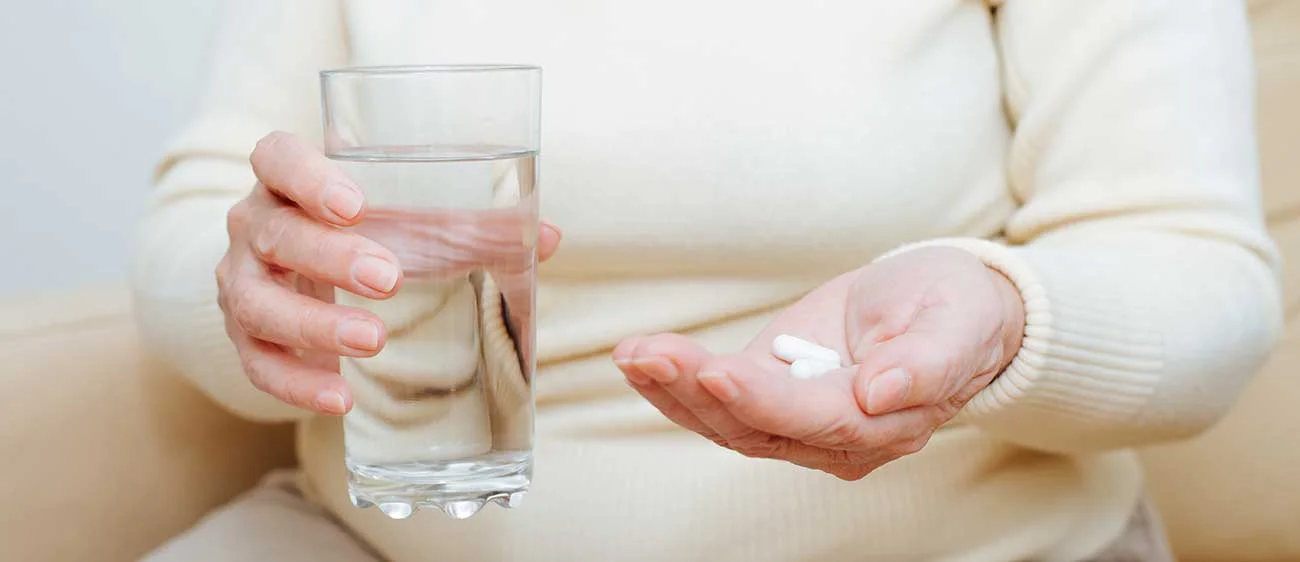 what is metformin Woman hodling metformin pills in one hand and a glass of water in the other