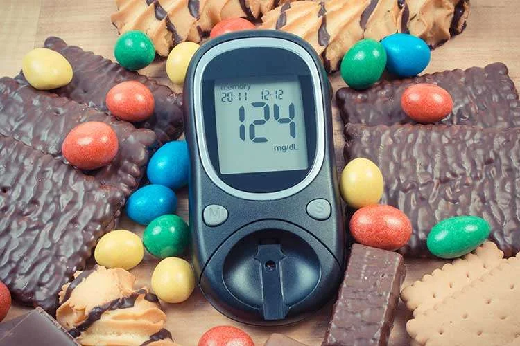 Glucometer showing blood sugar results and chocolate