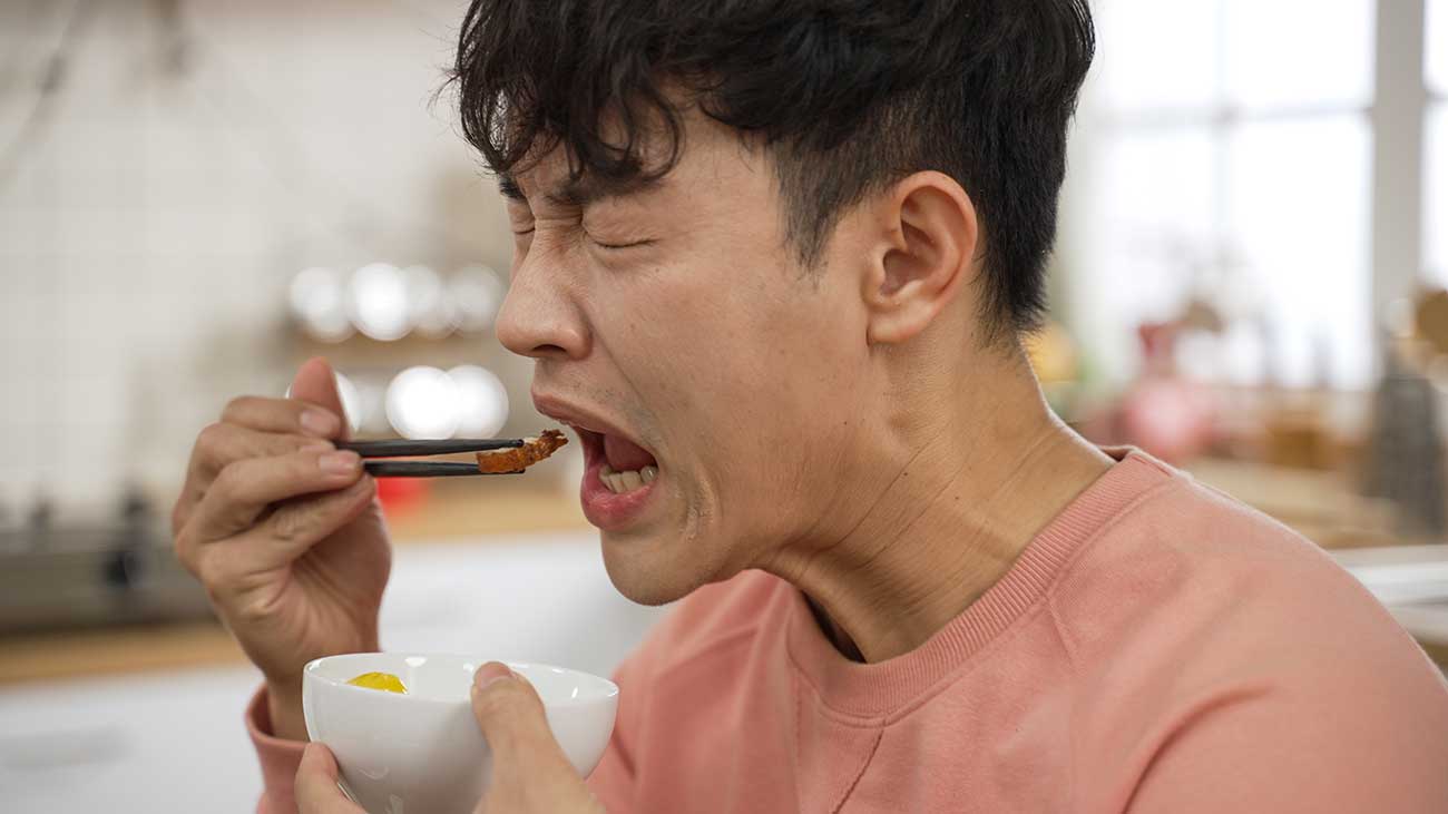 a man making funny facial expressions while tasting food
