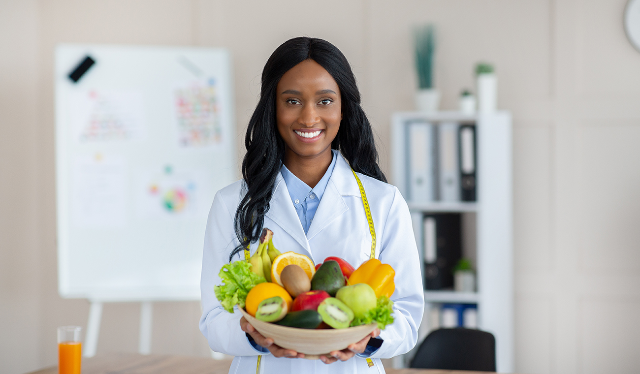Smiling nutritionist holding a basket of fruits